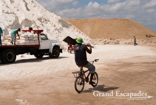There, the salt is collected in artificially made pans. In the nearby plant it is cleaned from sand and then piled up in a huge pure white mountain, a majestic sight. It is finally scooped into bags of approx. 50 to 60 kilograms and then heaved onto trucks